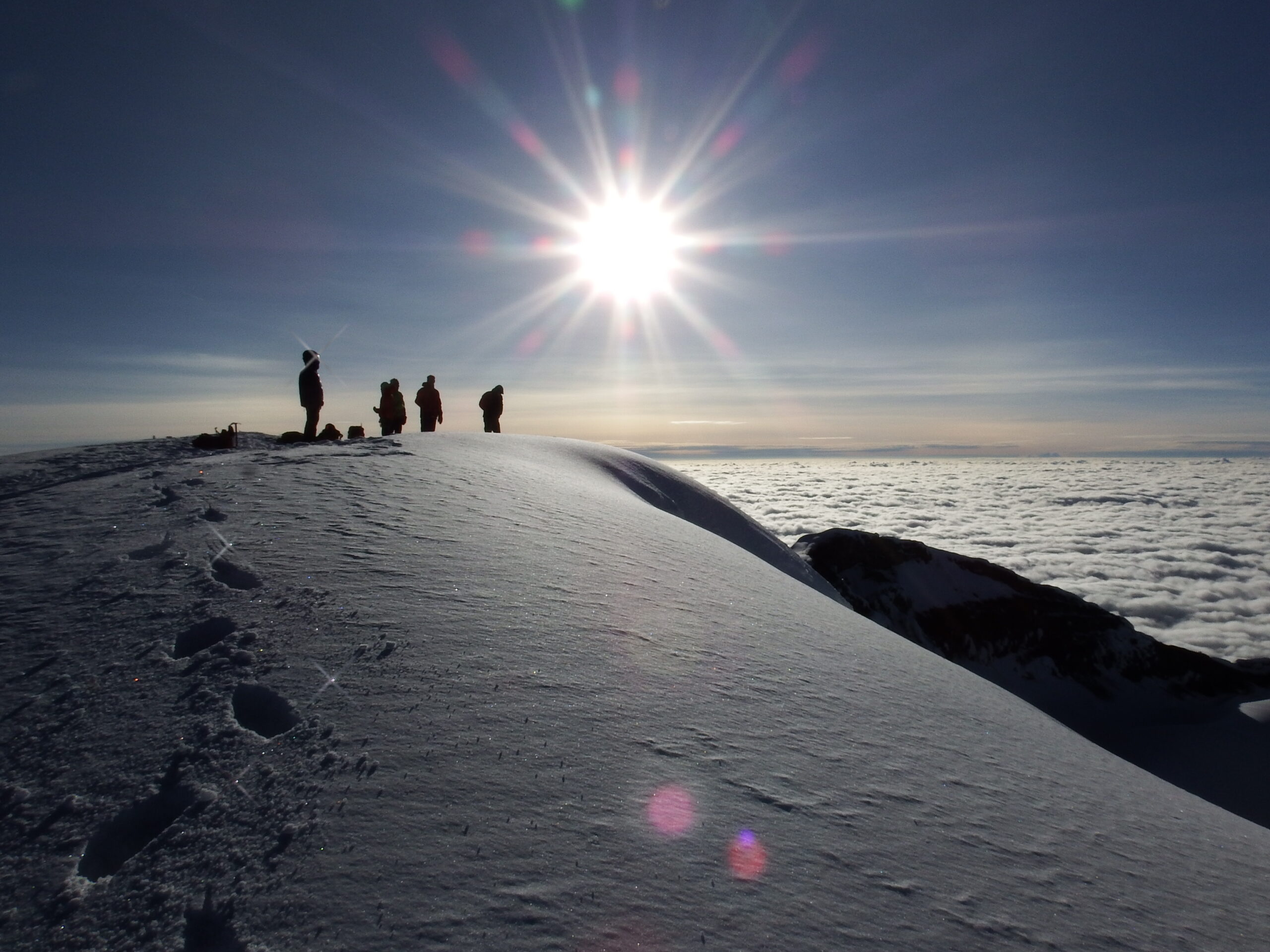 Climbers standing on Cotopaxi’s snow-covered summit above the clouds in Ecuador
