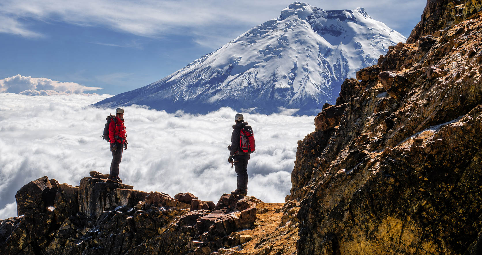 Climbers admiring the Cotopaxi volcano above the sea of ​​clouds